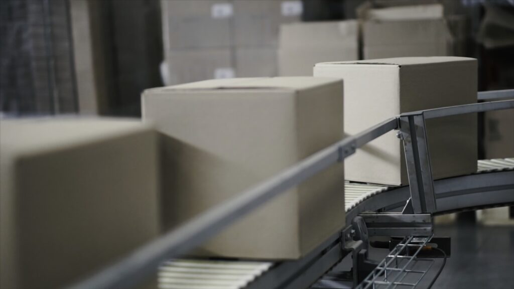 máquina etiquetadora Nosotros cardboard boxes on conveyor belt in factory clip 2024 12 06 06 09 05 utc Medium 1024x576